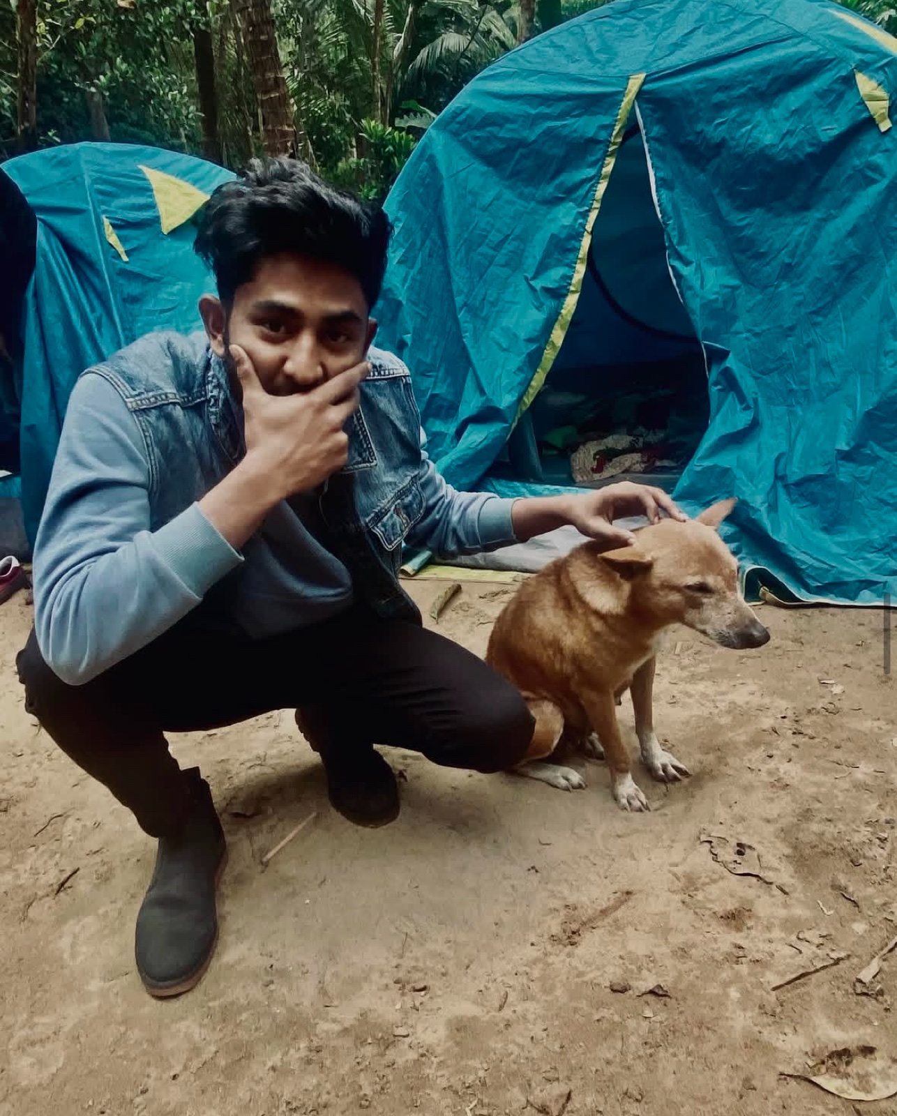 Naim with a dog beside tents at a campsite