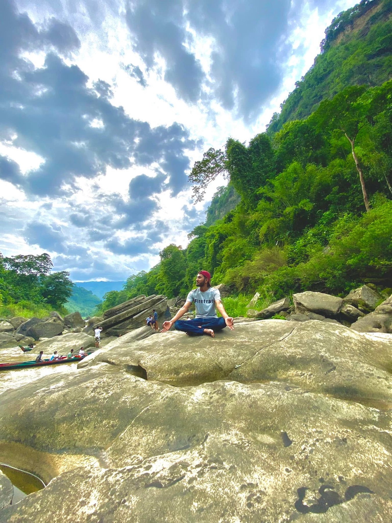 Naim sitting on a rock during a river and mountain adventure